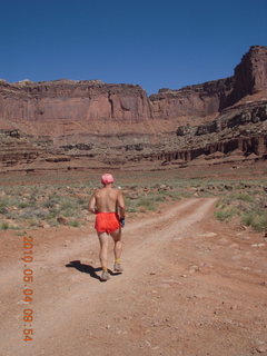 31 774. Canyonlands Lathrop Trail hike - Adam running on white rim road - back