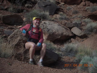 1408 7j7. Canyonlands Lathrop hike - Adam sitting on neat rock (tripod)