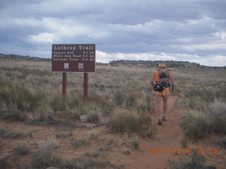 1422 7j7. Canyonlands Lathrop hike/run - Adam running with sign