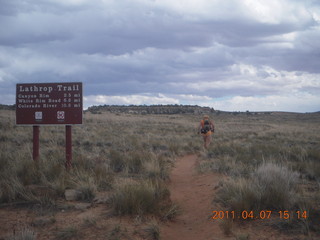 1423 7j7. Canyonlands Lathrop hike/run - Adam running with sign