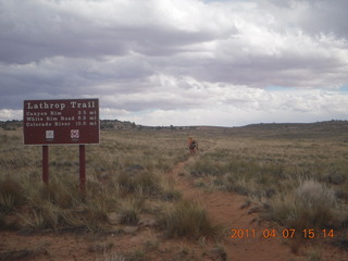 1424 7j7. Canyonlands Lathrop hike/run - Adam running with sign
