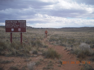 1425 7j7. Canyonlands Lathrop hike/run - Adam running with sign