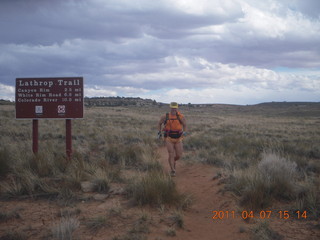 1427 7j7. Canyonlands Lathrop hike/run - Adam running with sign
