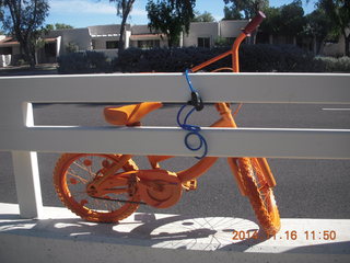 orange bike chained to a road fence